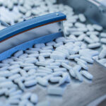 Tablets_and_Capsules_Manufacturing_Process._Close-up_Shot_of_Medical_Drug_Production_Line._White_Painkiller_Pills_are_Moving_on_Conveyor_at_Modern_Pharmaceutical_Factory.