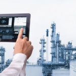 Man_hand_holding_cell_phone_or_tablet__automate_wireless__in_smart__oil_and_chemical_refinery__factory._Adobe_Stock